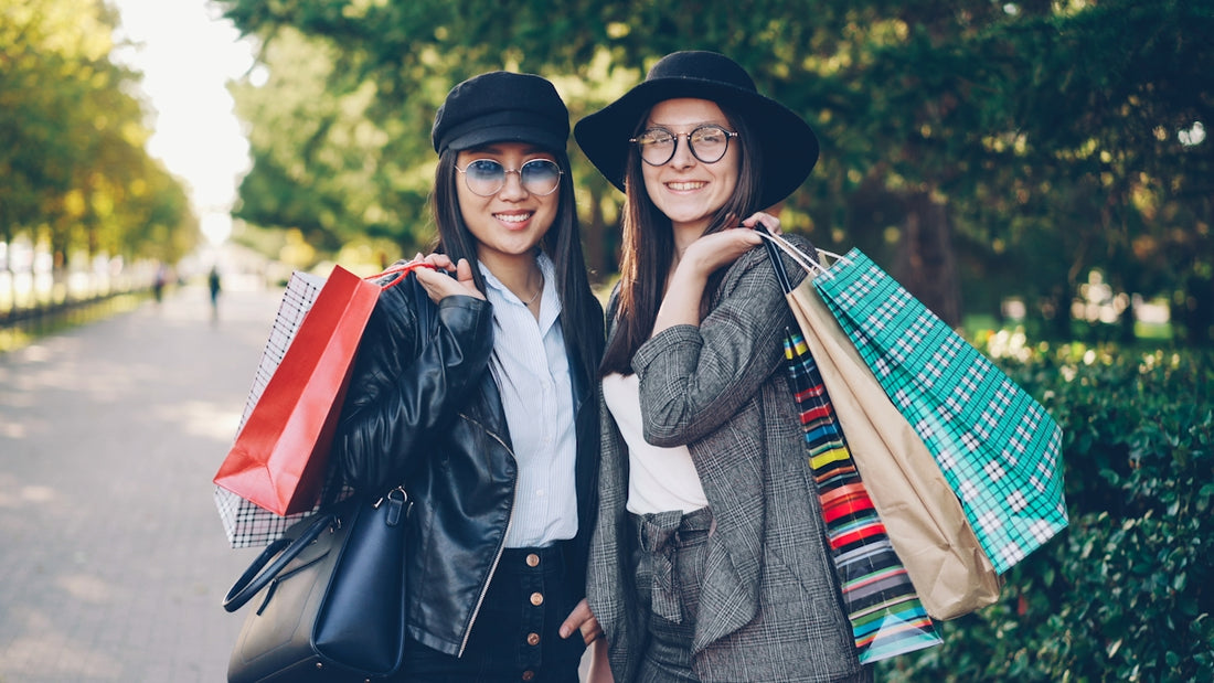 Two smiling women holding shopping bags outdoors