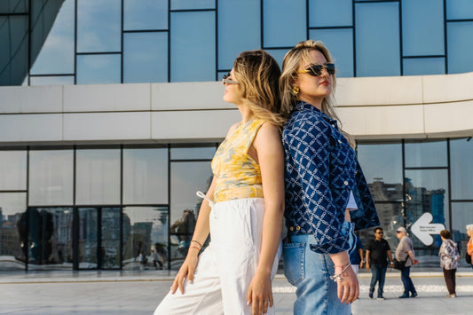Two women stand back to back outdoors