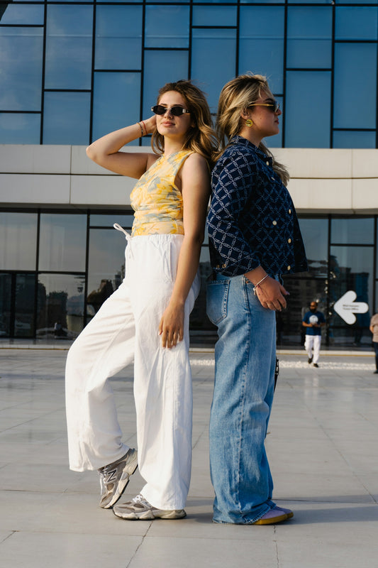 Two young women standing back to back outdoors